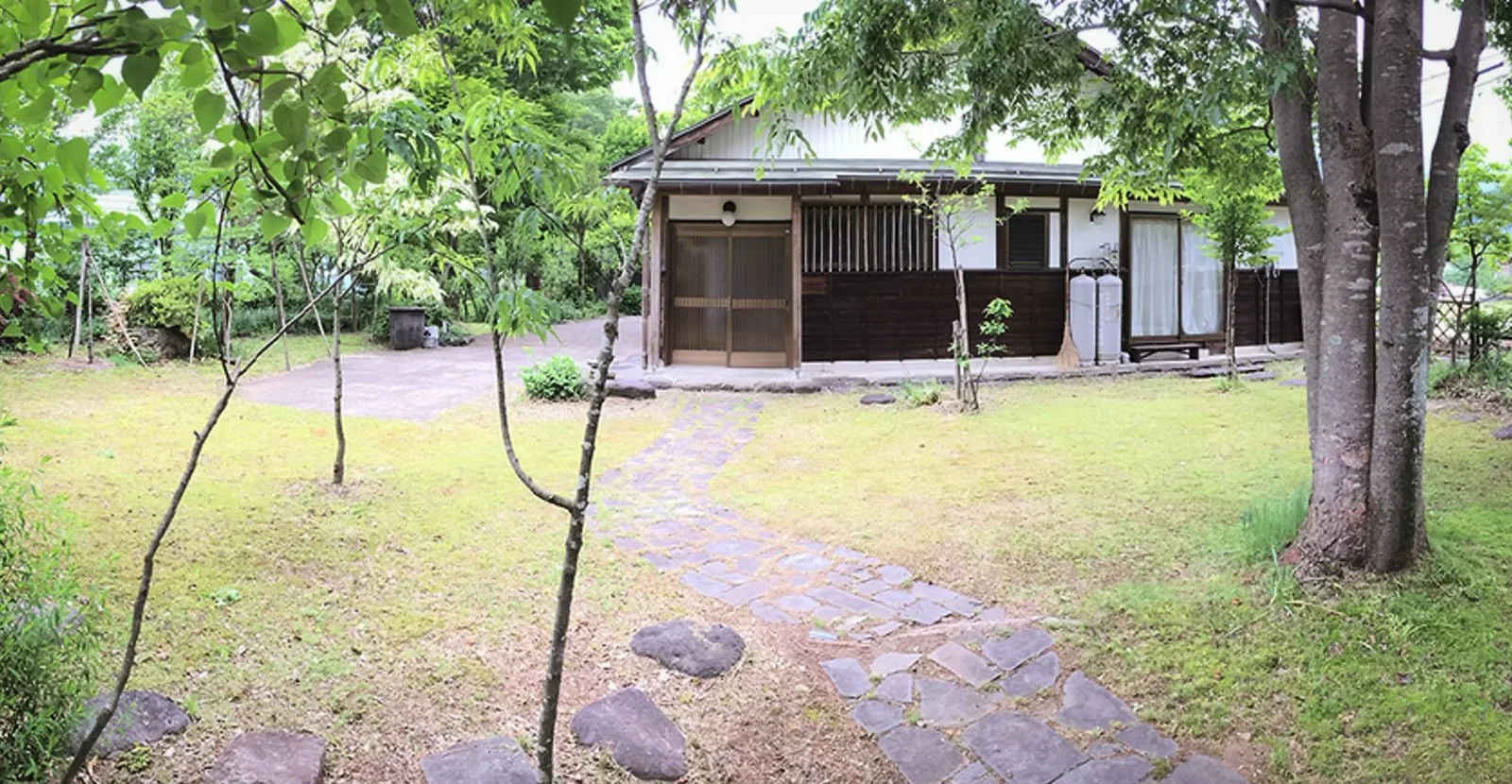 芝生の庭と石畳の小径の先に建つ母屋